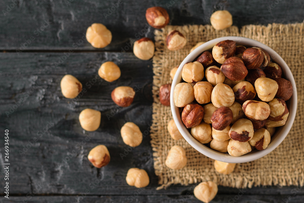 Scattered on the table roasted hazelnuts on a black wooden table. Prepared with the harvest of hazelnuts. Flat lay. Scattered on the table roasted hazelnuts on a black wooden table. Prepared with the harvest of hazelnuts. Flat lay.