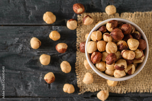 Scattered on the table roasted hazelnuts on a black wooden table. Prepared with the harvest of hazelnuts. Flat lay.