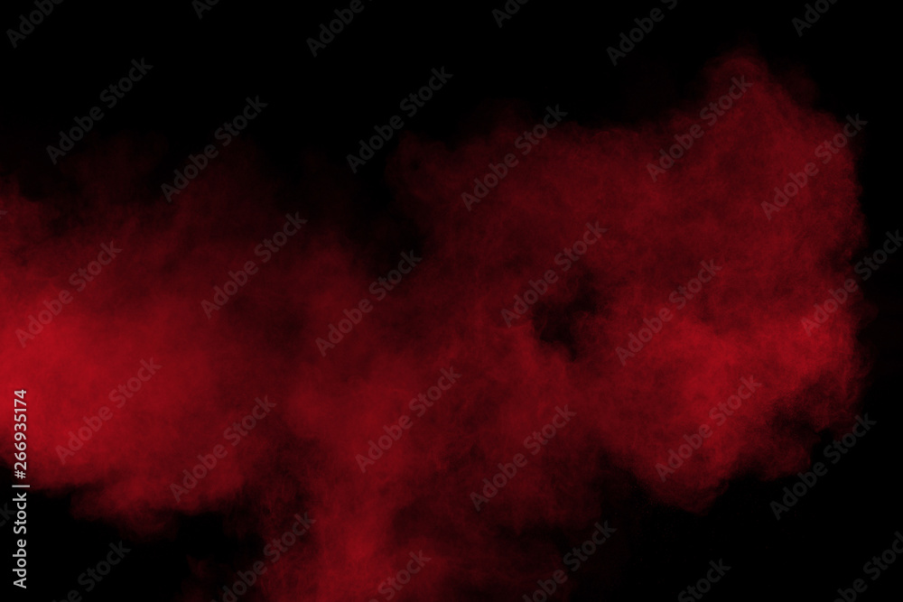 Red color powder explosion on black background. Freeze motion of red dust particles splash.