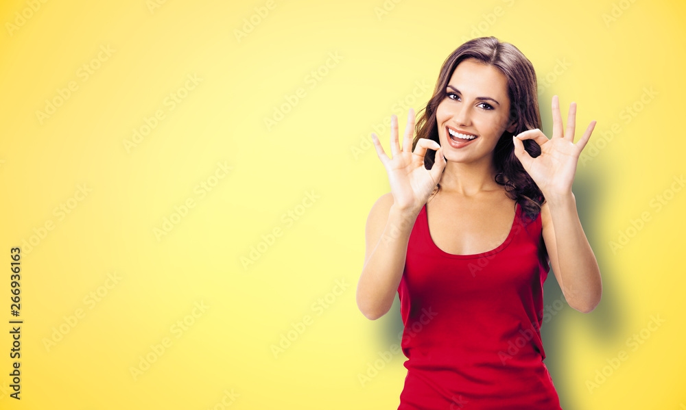 Photo of woman showing okay gesture, on yellow Photo of woman showing okay gesture, on yellow