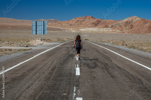 Rear view of woman walking along road in the desert © F.C.G.