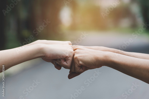 closeup hand of person team work fist bump in nature background. © mintra
