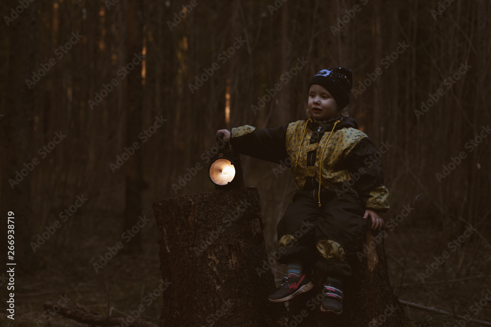 Fototapeta premium little baby alone in the dark forest with a flashlight