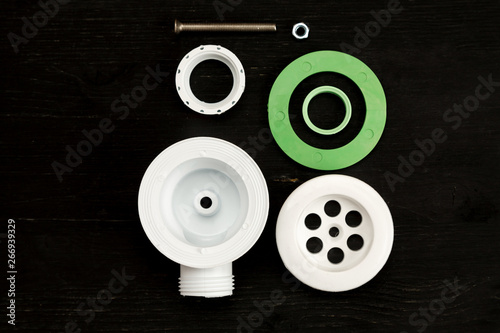 Parts of sink drain kit on a black background, top view, selective focus. Plumbing concept.