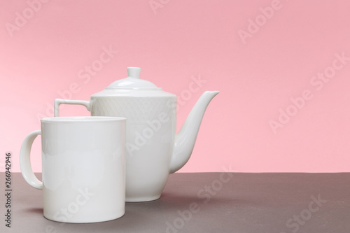 vintage white porcelain teapot and cup on a gray board and pink background