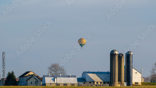 Hot air balloon floating above an Amish farm house, Lancaster County, PA