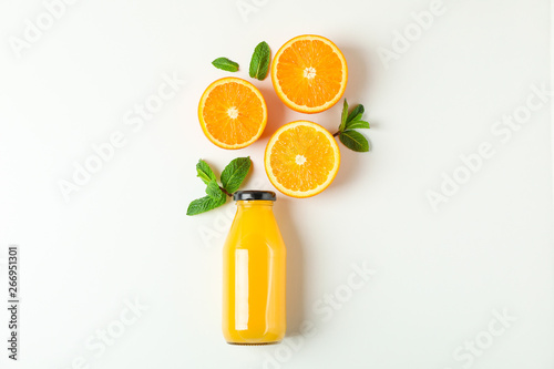 Flat lay composition with orange juice in bottle, oranges and mint on white background, space for text. Citrus drink and fruits