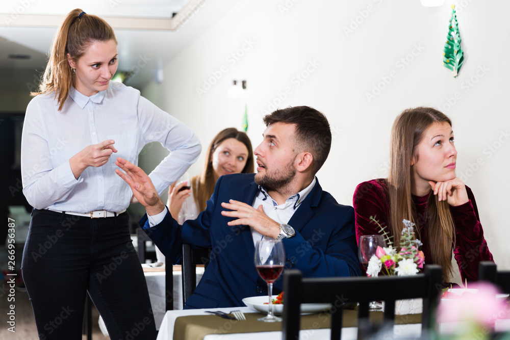 Young woman is dissatisfied in time her boyfriend is talking with woman in restaurante
