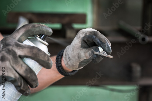 Worker with protective gloves painting the metal part