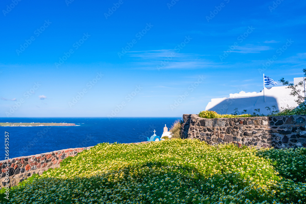 Santorini landscape with wild flowers and Aegean Sea in Oia, Greece
