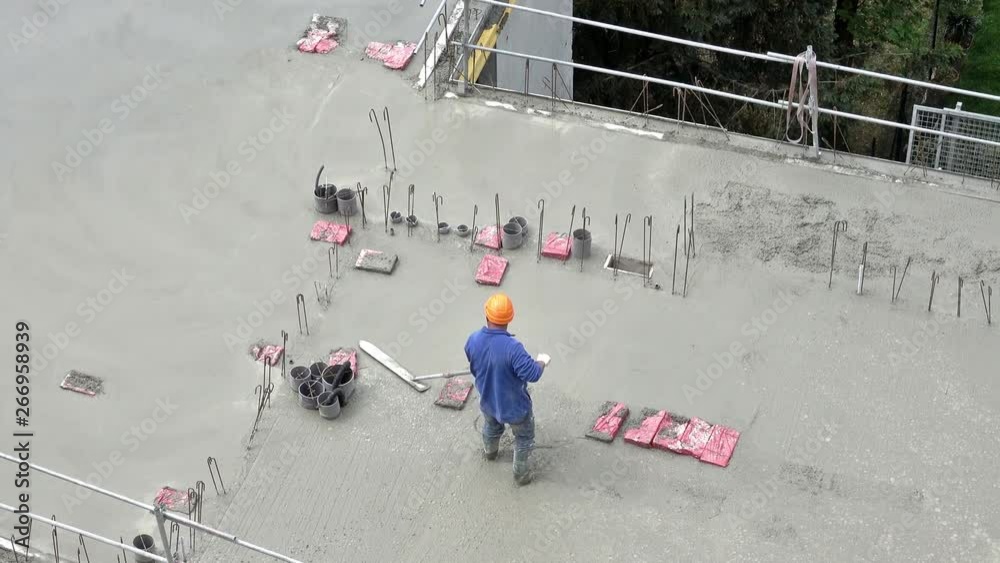 Un maçon coulant une dalle de béton sur le chantier d'un immeuble en construction