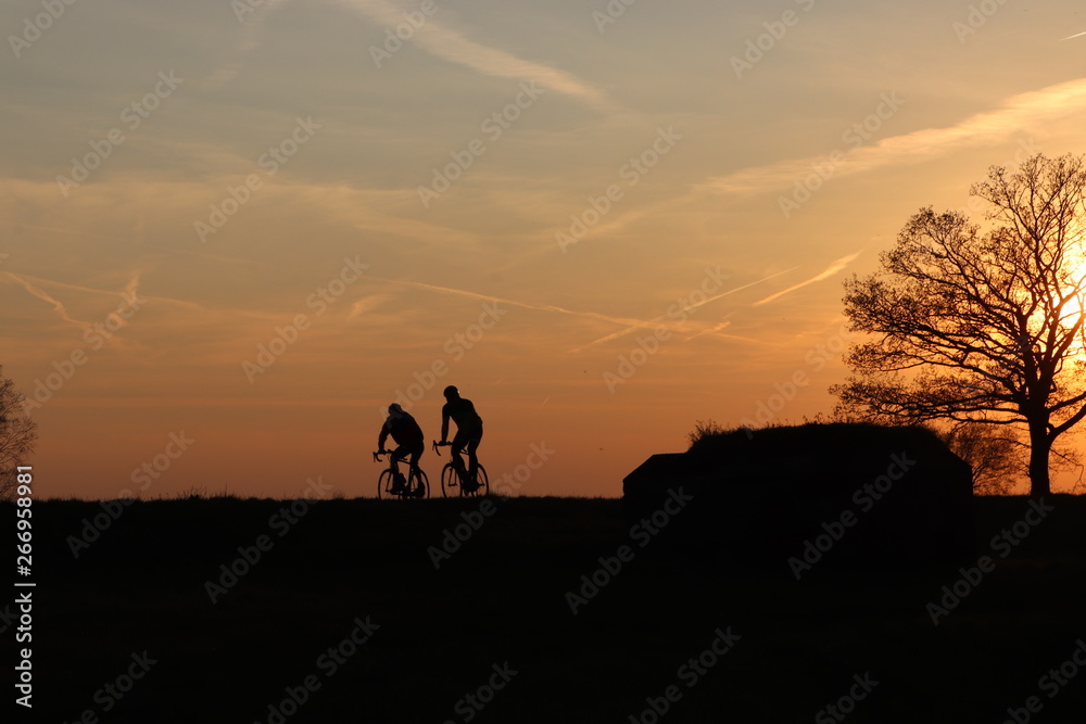 Two racing cyclists, silhouette at sunset