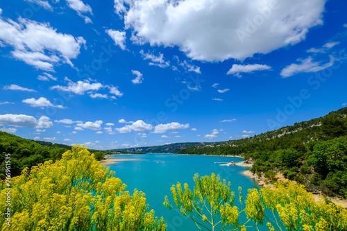 Vue panoramique sur le  lac de Sainte-Croix au printemps  ciel bleu avec de beaux nuages  fleur de gen  t au premier plan. Provence  France. Gorges du Verdon. 