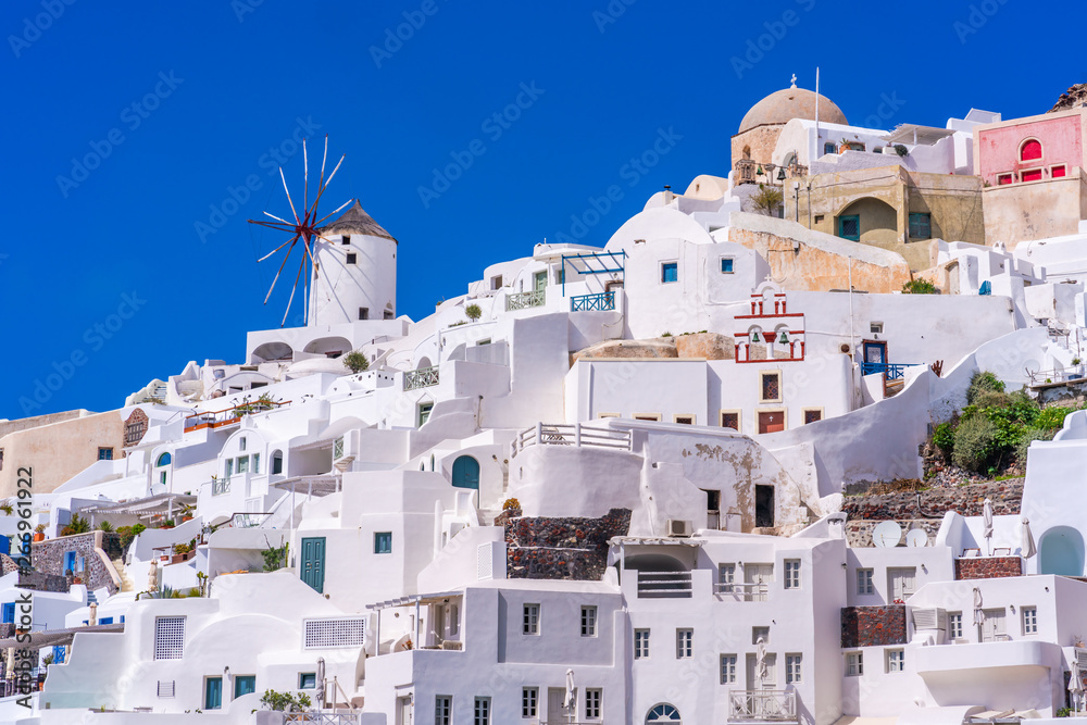 Fototapeta premium Santorini landscape with view of whitewashed buildings and windmills in Oia, Greece