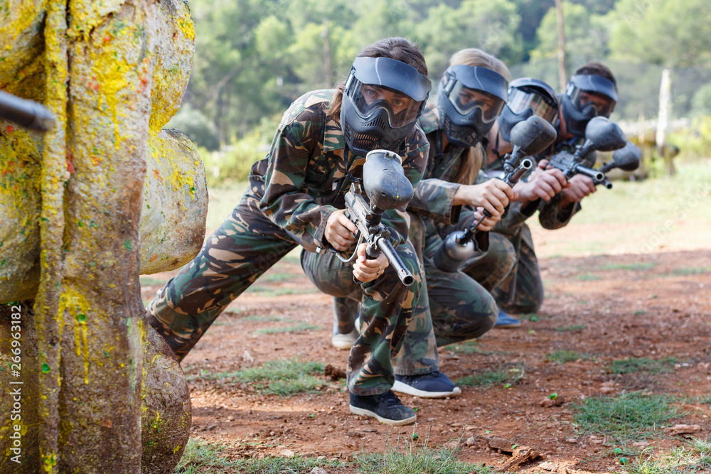 Portrait of team of adult people playing on paintball battlefield outdoor