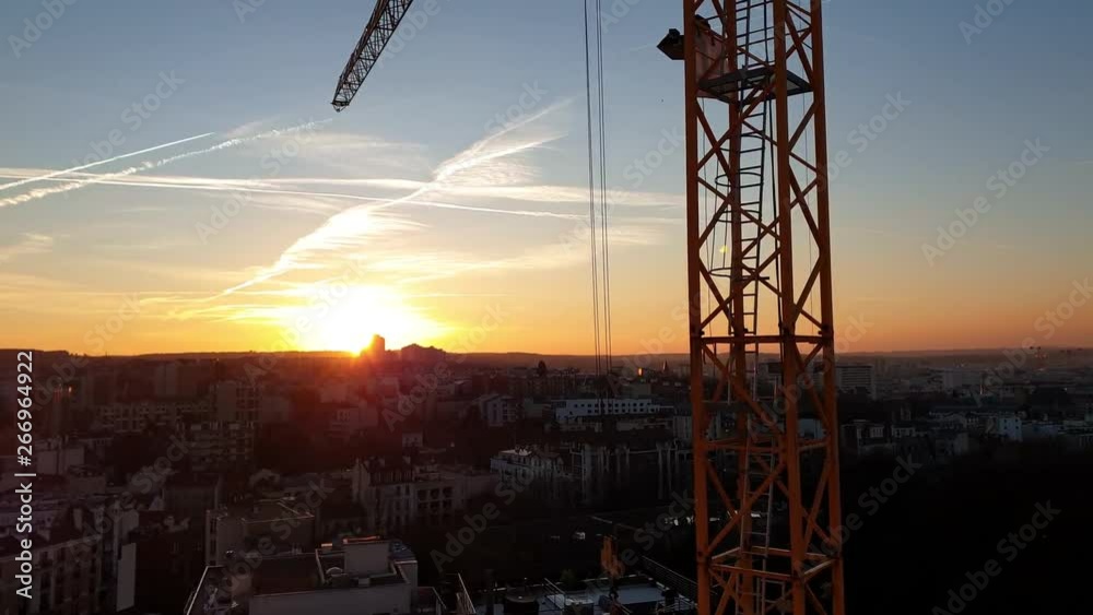 Une grue en fonctionnement sur le chantier d'un immeuble en construction au crépuscule