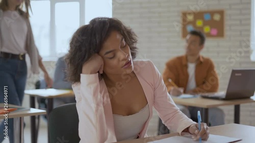emaciated simple woman sleeps in a lecture. black girl wakes up with a sudden jolt. Group of students in the background 4K