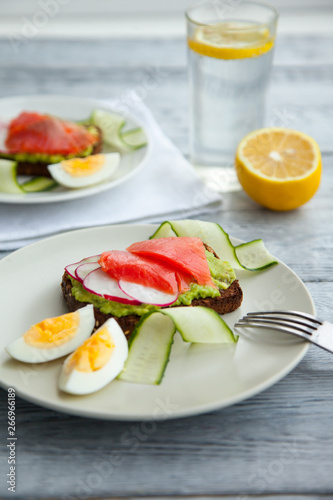 Toast sandwich with Salmon, Avocado,eggs and cucumber on plate on a table