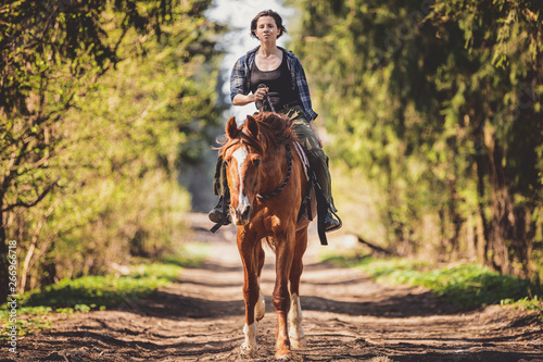 young woman riding horse in the forest in the spring