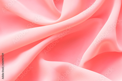 pink silk texture. background of coral fabric lying folds on the table