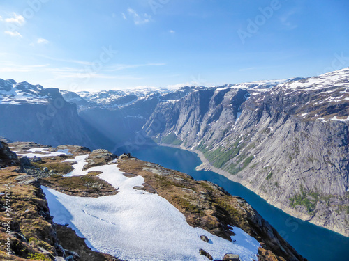 A beautiful view from the above on Ringedalsvatnet lake, Norway. Lake is located in between tall mountains. Slopes of the mountains are partially covered with snow. The water of the lake is navy blue.