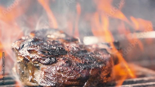 Large grains of pepper fall on juicy grilled filet mignon. Hot juicy oil steak cooking. Caucasian kitchen tasty beefsteak, delicious juicy meat. Street food cooked on hot plate. close up slow motion photo