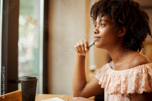 Foto Side view of thoughtful businesswoman with curly hair looking through window whi