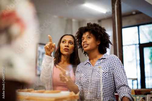 Canvastavla Female friends discussing while standing in cafe