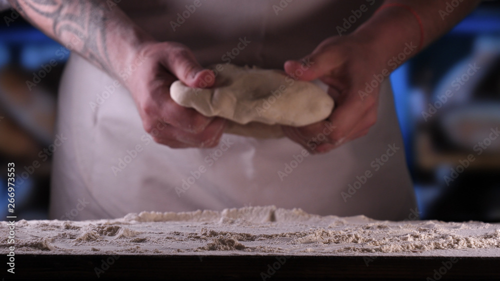 In the bakery, the hands of the baker are seen very closely as he prepares various flour products in an apron, after which he lays on the shelf. Concept of: Fresh Bread, Pizza, Bakery, Slow Motion.