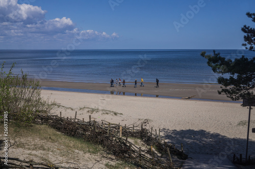 Beautiful view of the Gulf of Riga in the early spring. The sea is calm.A group of people walking along the shore.