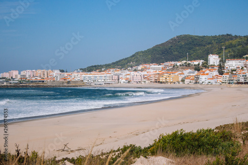 Wide empty beach with beautiful waves and white town on background. Vila Praia de Ancora, Portugal, landmark. Panoramic Atlantic Ocean coast with calm beach. White sand shore. Europe travel concept. © Nataliia