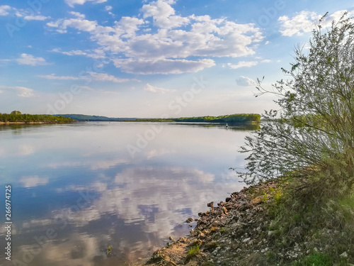 Spring sky in the clouds reflected in a deep river. © Roman52stock