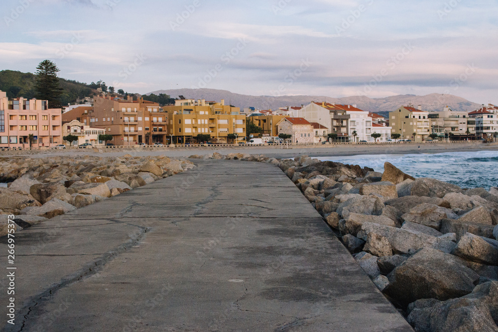 Vila Praia de Ancora, Portugal - 15/10/2018: Empty pier with stones and town in the evening. Calm coastal town landmark. Europe travel concept. Bay village background. 
