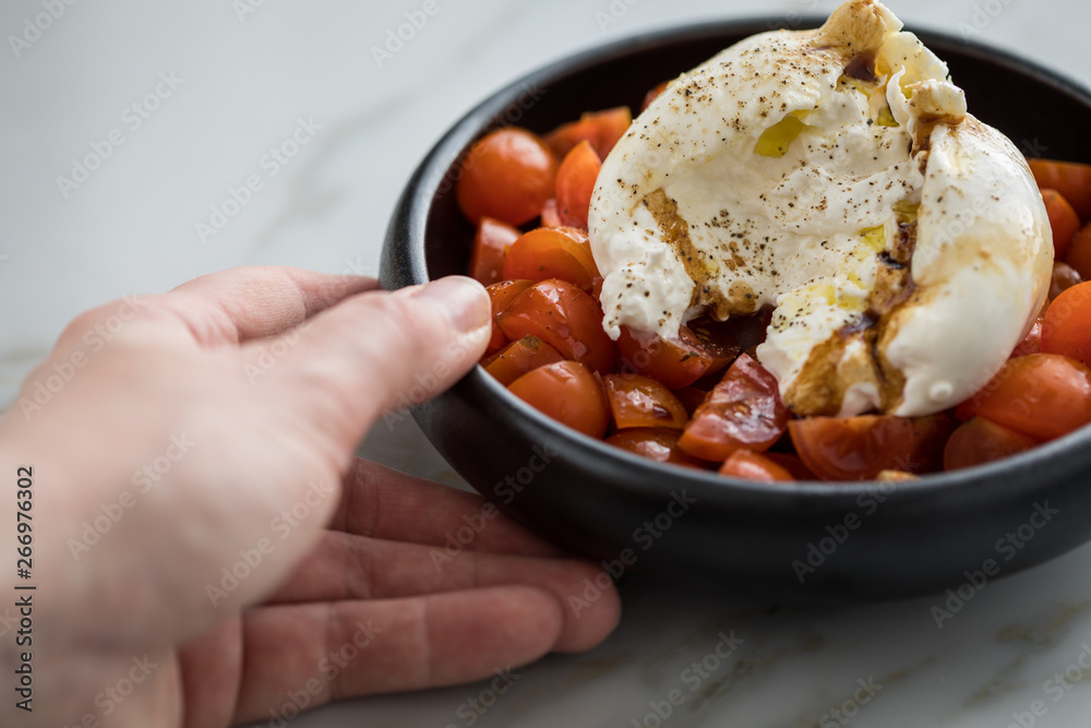 Frau isst Burrata Büffelmozzarella Kugel mit Tomaten, Olivenöl und Balsamico auf schwarzen Teller Frau isst Burrata Büffelmozzarella Kugel mit Tomaten, Olivenöl und Balsamico auf schwarzen Teller