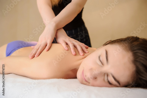 lateral view of a young woman having a massage on her back in spa salon