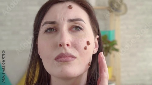 Young sad woman with moles on her face looking in the mirror slow mo photo