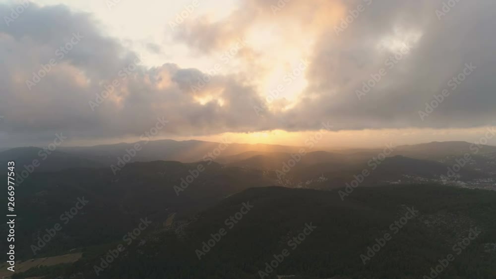 Flying slowly down to the dense dark mountain forest. Beautiful view of clouds and amazing golden hour sunset with beams of the sunlight. Aerial cinematic 4K drone footage Flying slowly down to the dense dark mountain forest. Beautiful view of clouds and amazing golden hour sunset with beams of the sunlight. Aerial cinematic 4K drone footage