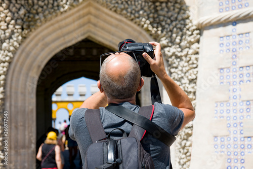 Cintra. The Pena Palace. Adult man takes pictures of the arch on a professional camera. The man is depicted behind. photo