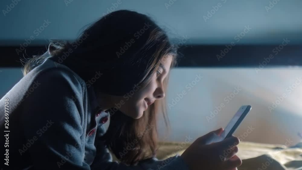 Vidéo Stock girl teenager and smartphone. little teen hood lifestyle girl writes a message chatting in social media messenger night evening indoors smartphone on the bed. children technology and communication | Adobe Stock 