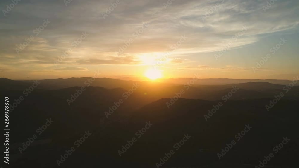 Flying back slowly over dense mountain forest. Beautiful view of clouds and amazing golden hour sunset with beams of the sunlight. Aerial cinematic 4K drone footage Flying back slowly over dense mountain forest. Beautiful view of clouds and amazing golden hour sunset with beams of the sunlight. Aerial cinematic 4K drone footage