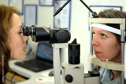 pretty young woman undergone an ocular fundus inspection with ophthalmologist optometrist optician, low depth of field