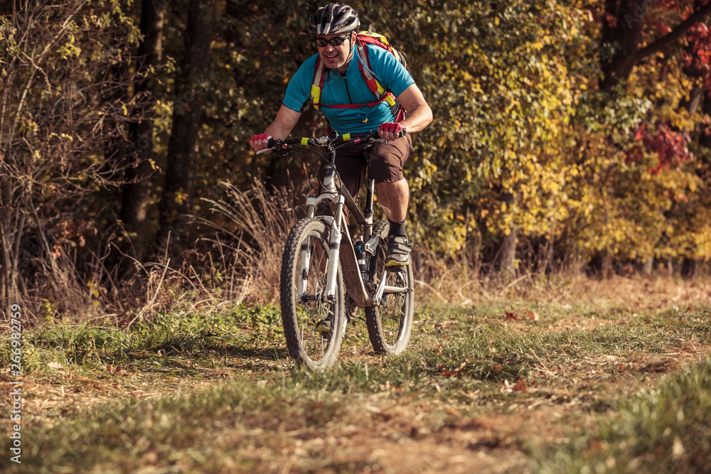 Man riding mountain bike on path by the forest Man riding mountain bike on path by the forest