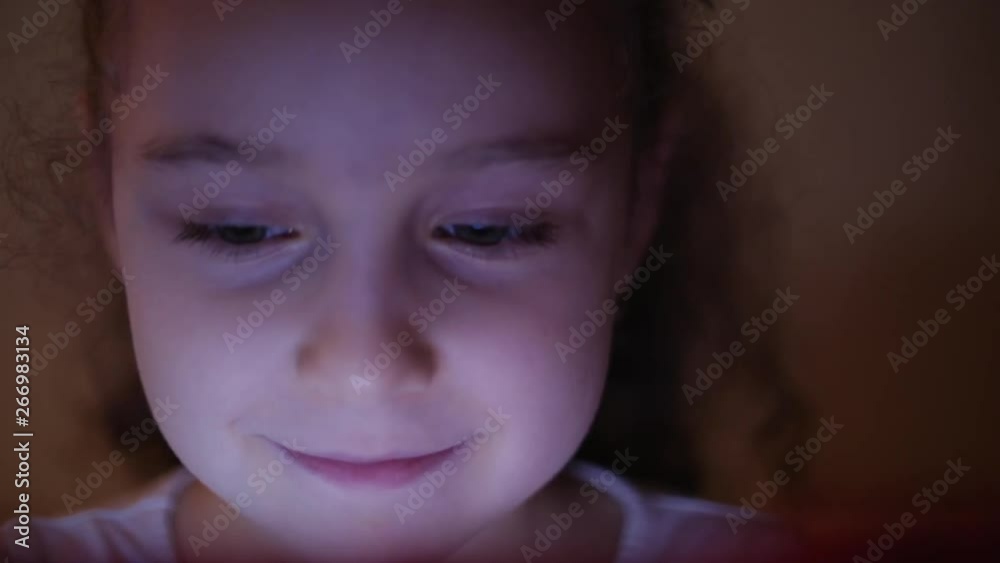 Night Shot of a Cute Caucasian Little Girl Close Up of a Child's Face Viewing a Tablet PC With a Reflection of Pight and Pictures in His Eyes Night Shot of a Cute Caucasian Little Girl Close Up of a Child's Face Viewing a Tablet PC With a Reflection of Pight and Pictures in His Eyes