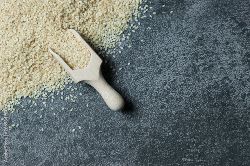 raw sesame seeds in wooden shovel on grey rustic table. Uncooked sesame background concept with copy space