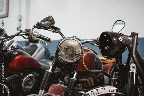 Shabby vintage motorbikes with broken headlights parked inside repair workshop photo