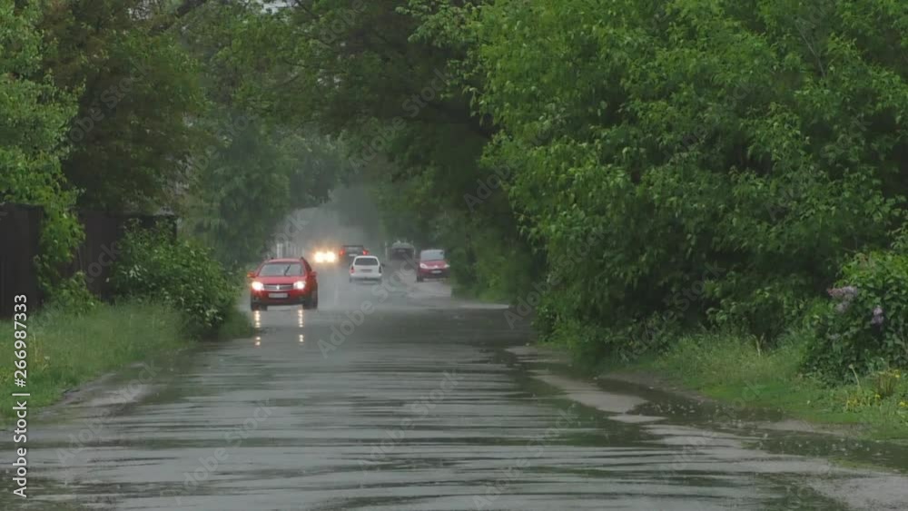 Heavy spring rain floods the streets with cars on the road and people passing by. Heavy spring rain floods the streets with cars on the road and people passing by.
