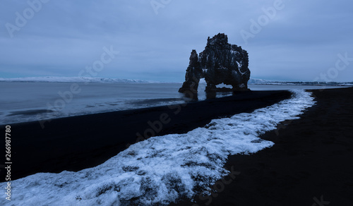 Picturesque view of pebble beach of seashore with rocks in water under gloomy sky in HvÌtserkur Iceland