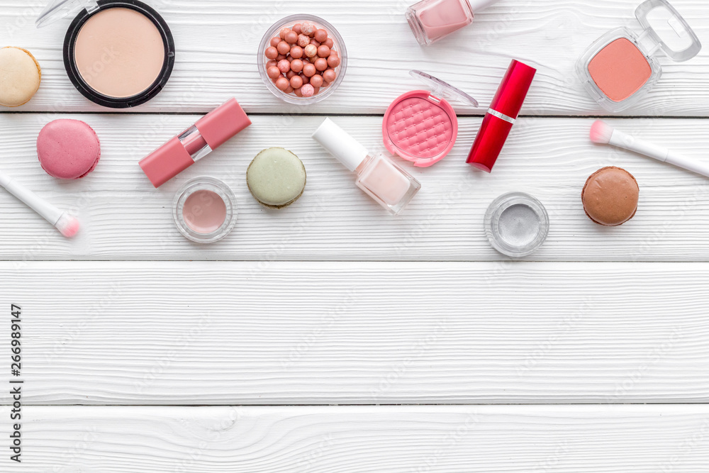 decorative cosmetics for make-up with macaroon cookies on white wooden tabletop background copy space decorative cosmetics for make-up with macaroon cookies on white wooden tabletop background copy space