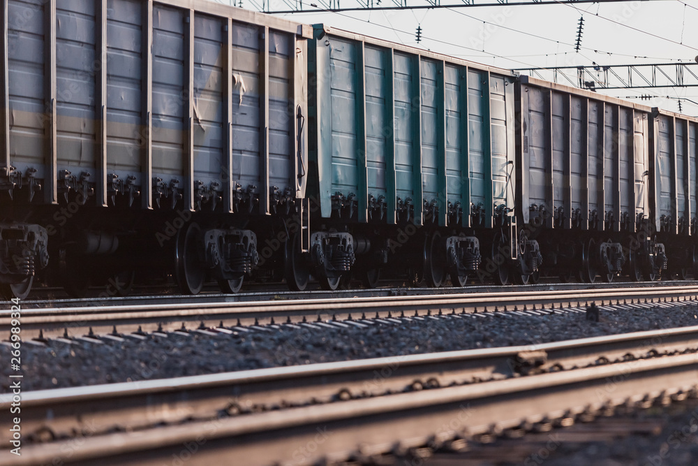 The train is on the railway track. Many cars with cargo in the rays of sunset lighting. The train is on the railway track. Many cars with cargo in the rays of sunset lighting.