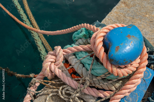 Close-up of a blue metal bollard with knotted nautical ropes on a pier of an harbor, Sestri Levante, Liguria, Italy